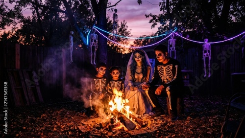 Holidays - Family in Halloween costumes sitting by a campfire in a backyard at dusk