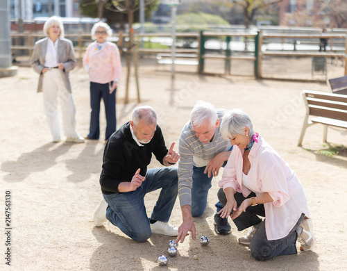 Cuadro en lienzo Active senior friends evaluating position of petanca ball while playing together