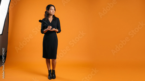Tapety artystyczne Young woman in black dress holding feather in studio