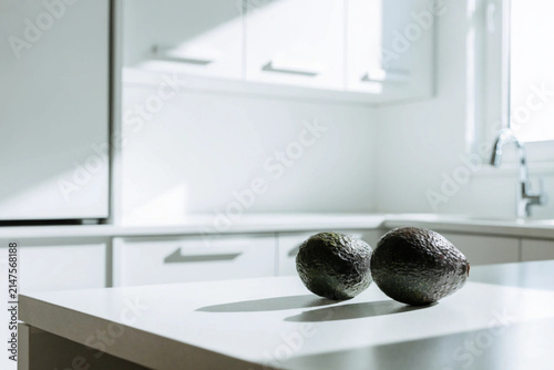 Fresh avocados on the white table in the white modern kitchen. Copy space