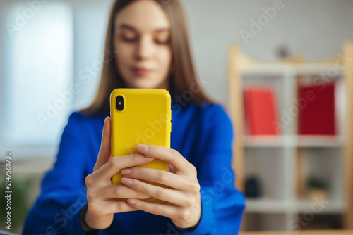 Close up of a woman holding a smartphone with a bright yellow case in her hands