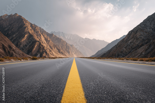 Low angle view of an empty asphalt road stretching towards high mountains