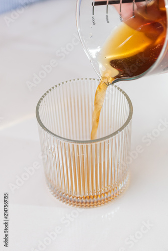 Obraz na plátne Hot black coffee poured into a transparent glass with smooth motion, modern cafe drink preparation