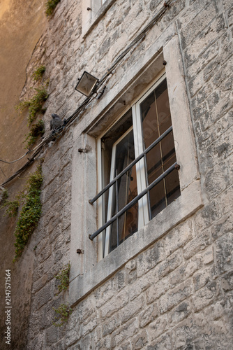 Historic stone building facades with traditional windows, shutters, and doors.