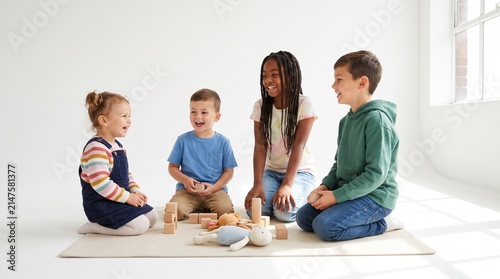 Four young children are happily playing with wooden blocks on the floor. They are sitting in a circle and smiling at each other, engaged in creative play