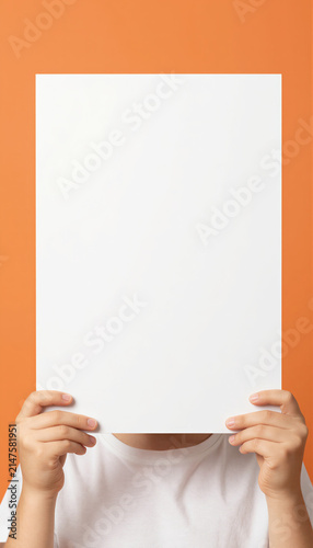 Person holding blank white paper sign against orange background