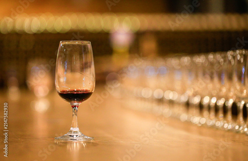 Glass of red wine placed on wooden table with out-of-focus empty wine glasses backdrop