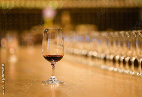 Glass of red wine placed on wooden table with out-of-focus empty wine glasses backdrop
