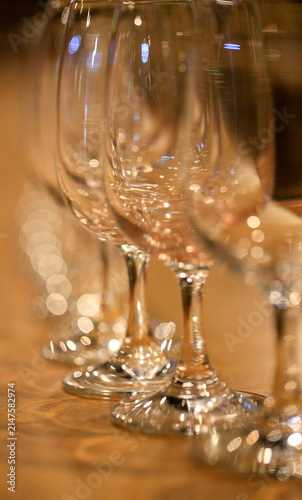 A row of neatly arranged empty wine glasses, inside the bar