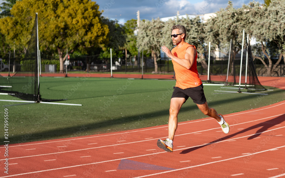 Fototapeta premium Sportsman runner running outdoor. Sport run. Muscular man running. Sportsman jogger running. Man sportsman running to exercise. Sport athlete man run. Runner at long sport run