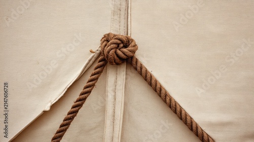 Close-up of taut triangular tent corner secured by rope.
