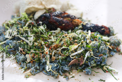 Fotografía A fully mixed serving of Malaysian Nasi Kerabu featuring fragrant blue pea flower rice, grilled chicken, raw vegetable and herb salad (ulam), and crispy fish crackers