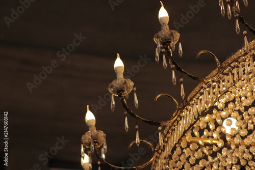 Bottom-up view of a large luxurious crystal chandelier with glowing warm lights.
