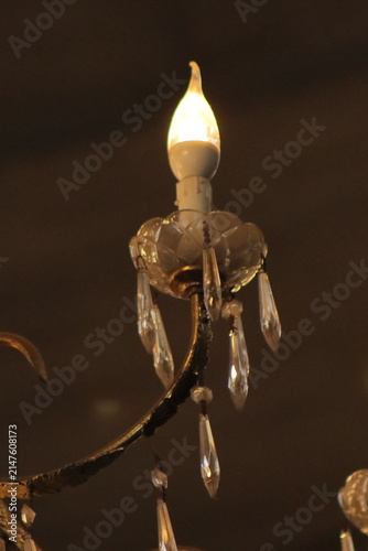 Bottom-up view of a large luxurious crystal chandelier with glowing warm lights.