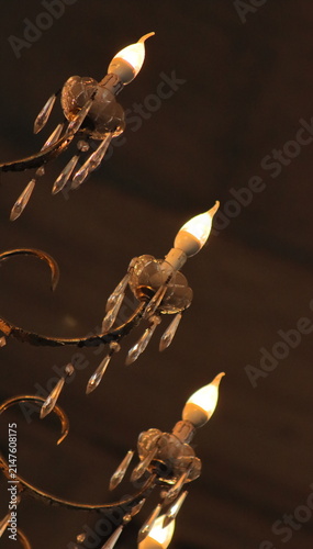 Bottom-up view of a large luxurious crystal chandelier with glowing warm lights.