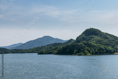 Canvastavla Serene lake surrounded by lush green mountains under clear blue sky with natural