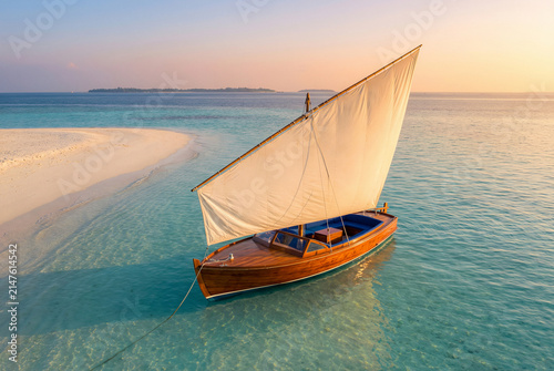 Wooden sailboat floating in clear turquoise water near sandy beach