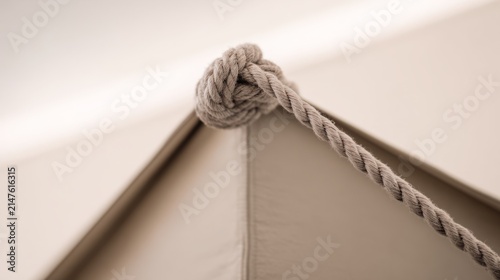 Close-up of taut triangular tent corner secured by rope.
