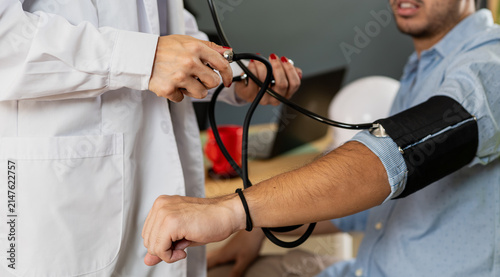 Foto Doctor checking blood pressure of young patient