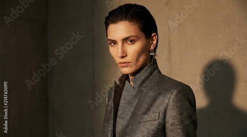 Intense portrait of a woman in grey blazer with dramatic lighting.
