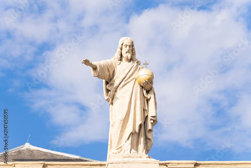 Obraz na plátně Low angle view of Salvator Mundi stone statue of Jesus Christ with golden globus