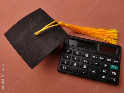 фотографія A black graduation cap with a yellow tassel sits beside a black electronic calcu