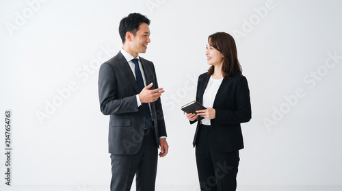 Photo of two company employees chatting, at work, white background, 