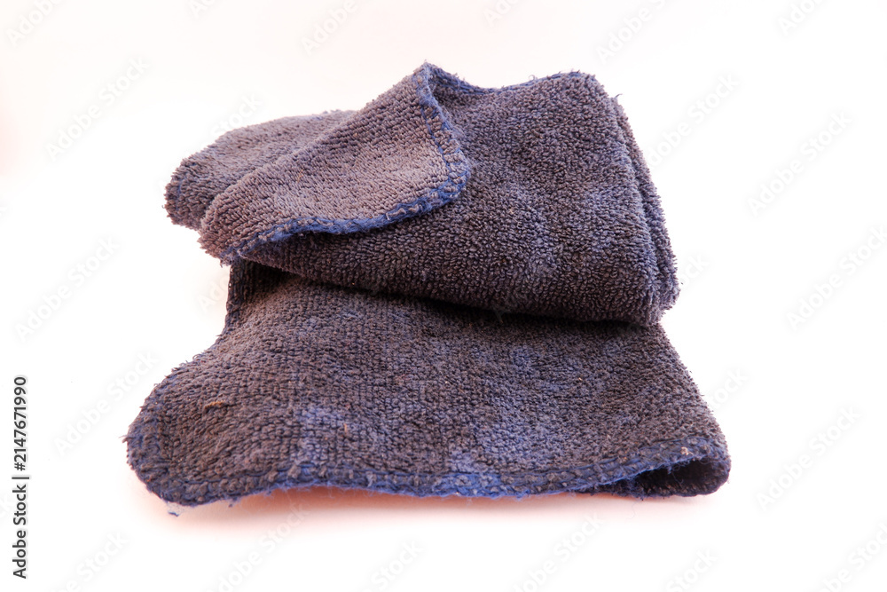 Fototapeta premium Dark blue microfiber cleaning cloth showing visible dirt and signs of wear after prolonged use. The fabric appears stained and slightly frayed along the edges, highlighting frequent use in household