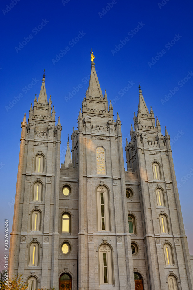 Fototapeta premium The Salt Lake Temple stands majestically in Temple Square in Salt Lake City, Utah, showcasing stunning Gothic and Romanesque architectural details. Its granite spires rise against a clear blue sky, su