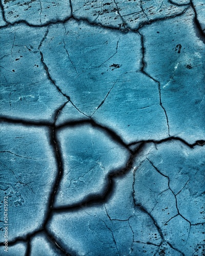 Abstract macro shot of a weathered blue cracked texture with deep black fissures, perfect for background design.