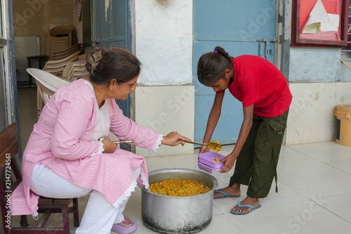 Cuadro en lienzo Indian woman serving food to underprivileged children in in rural india