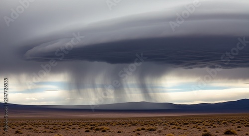 Ominous storm cloud over desert landscape with rain shafts
