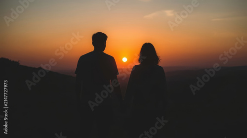 Silhouette couple holding hands at sunset over horizon