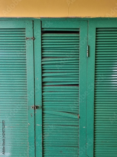 Konstfotografi Damaged green wooden louvered door with broken slatted blinds and weathered text