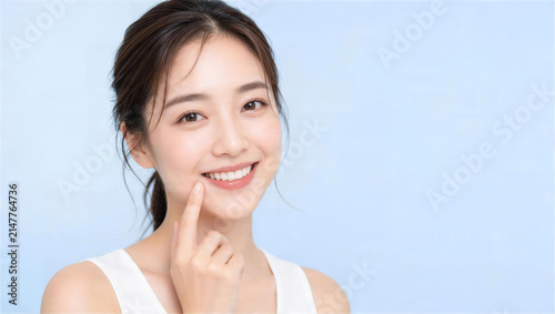 口元を指差して笑顔を見せる女性