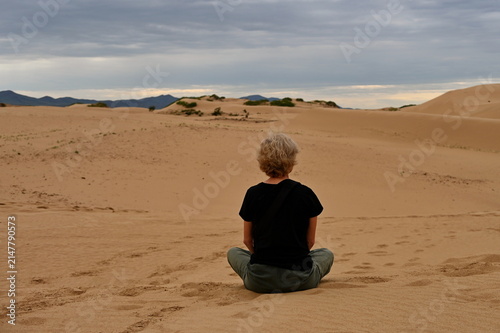 Rear view of mature woman sitting on sand dunes in Gobi Desert, Mongolia