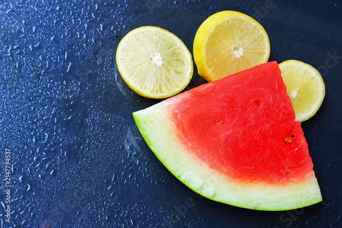 Fresh Watermelon Slice and Lemon Citrus on Dark Wet Background with Water Droplets