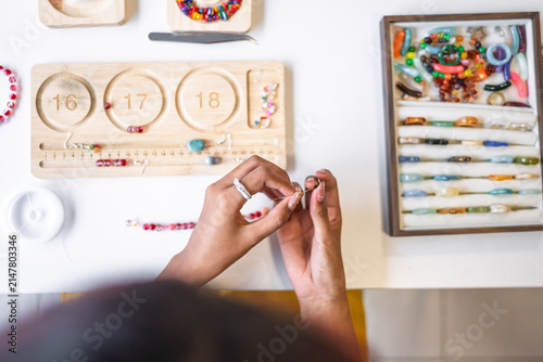 Asian woman making handmade beaded jewelry in creative workspace for artisan craft and small business creative entrepreneurship