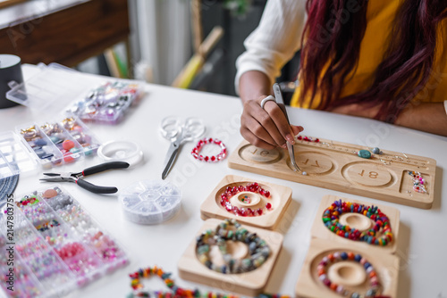Quadro su tela Asian woman making handmade beaded jewelry in creative workspace for artisan cra