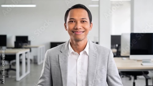 Indonesian business man investor, doubtful young male ceo executive wearing suit standing in office holding hand in chin looking away at work thinking on leadership question, feeling doubt.