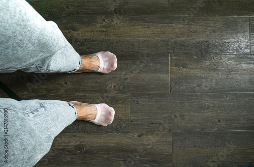 Top view of female feet in pink low cut socks on dark wooden floor