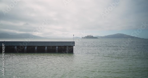 4K handheld cinematic view of Alcatraz Island from the San Francisco waterfront near Pier 39. The historic prison island sits across the bay with surrounding water. Pier in Foreground.