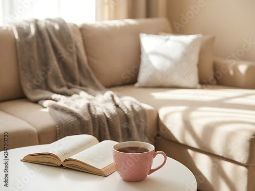 Cozy Sunlit Living Room with Sofa, Coffee Table, Open Book, and Steaming Tea Creating Warm Relaxation and Hygge Comfort