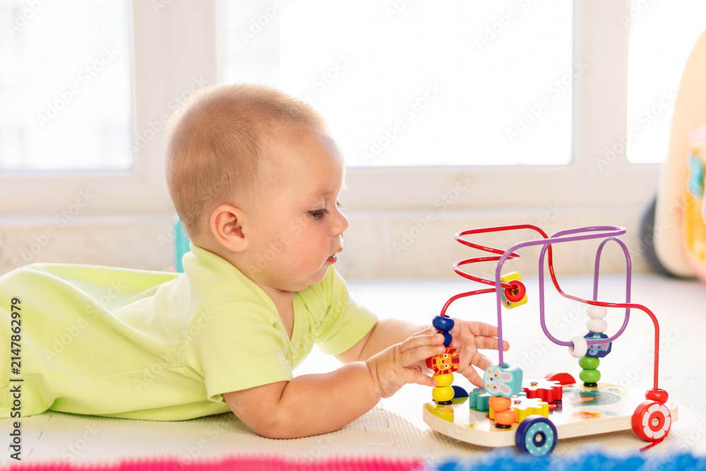Naklejka premium Infant Boy Practices Fine Motor Skills With Bead Maze