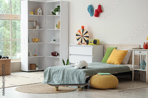 Фотография Modern teenagers bedroom with a single white shelving unit skateboard and colorf