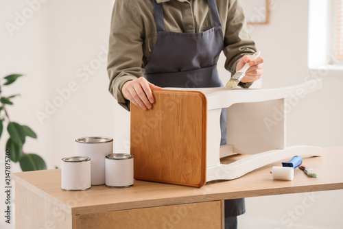 Person painting a wooden stool white, home improvement and furniture restoration project, diy hobby and creative activity