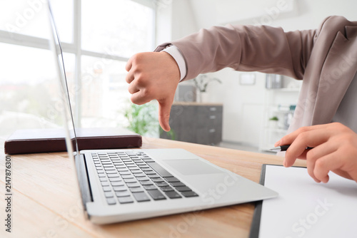 Принти на полотні Businessman giving a thumbs down gesture while working on a laptop at a modern o
