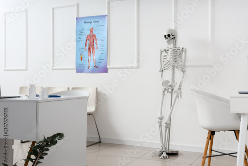 Interior of medical office with human skeleton model and desks