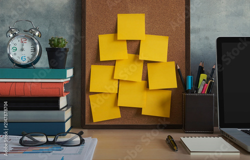 Quadro su tela corkboard with yellow sticky notes on desk with laptop books alarm clock and off