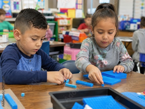 Young Elementary Students Focused on Math Lesson with Base Ten Blocks in a Bright Classroom Setting